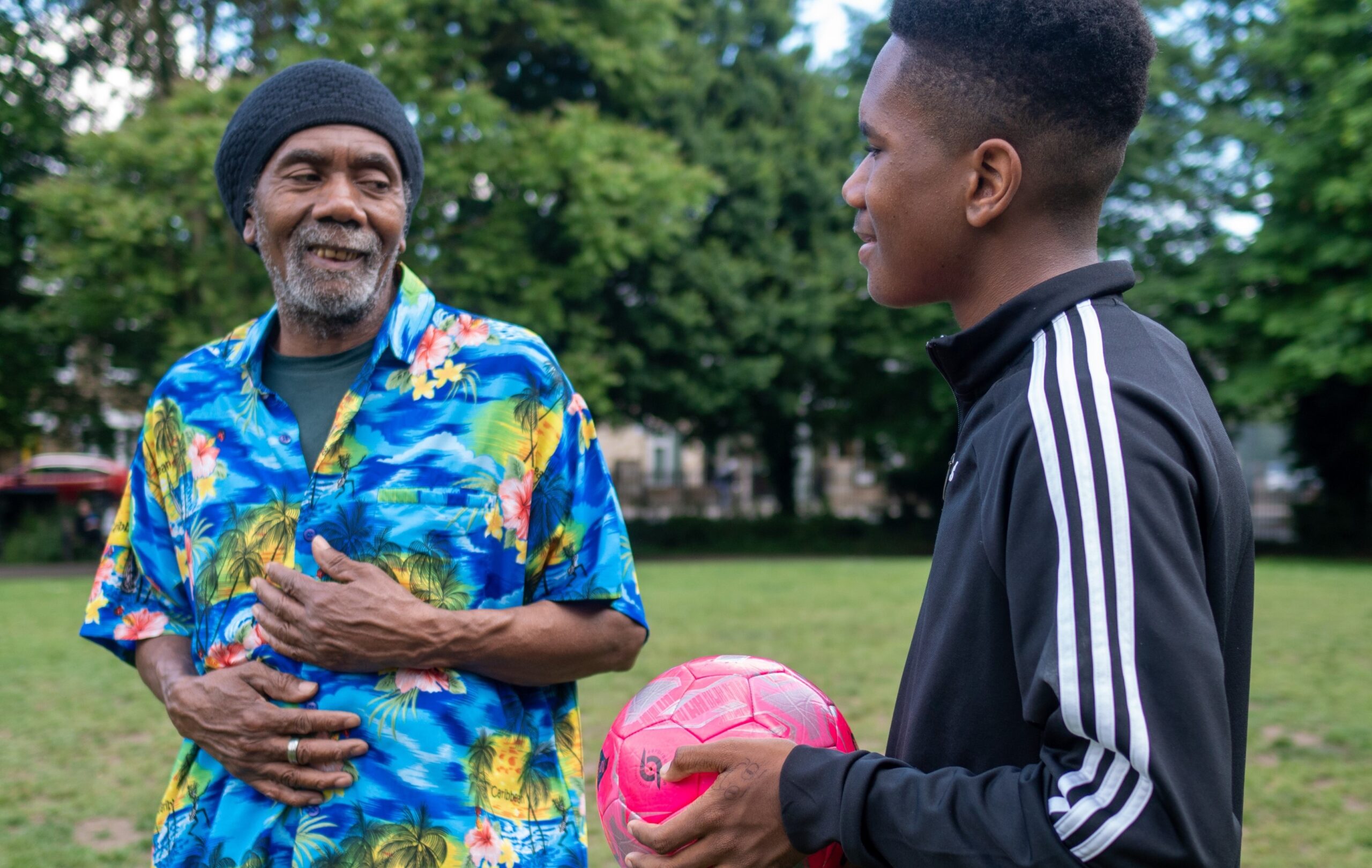 Un jeune garçon tenant un ballon de football et un homme plus âgé au milieu d'un terrain.